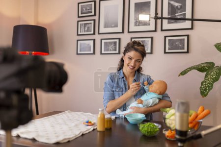 Téléchargez les photos : Vidéo d'enregistrement de vloggeuses sur l'introduction d'un aliment mou dans la nutrition du bébé et l'alimentation d'un bébé dans le cadre de cours prénatals en ligne - en image libre de droit