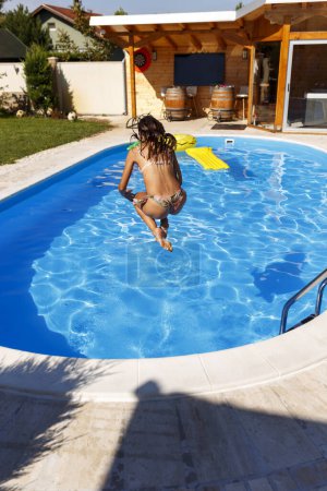Téléchargez les photos : Belle jeune femme qui s'amuse pendant les vacances d'été, sautant dans la piscine - en image libre de droit