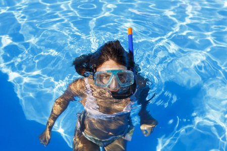Foto de Hermosa joven disfrutando mientras está en vacaciones de verano poniéndose una máscara de snorkel, divirtiéndose haciendo snorkel en la piscina - Imagen libre de derechos
