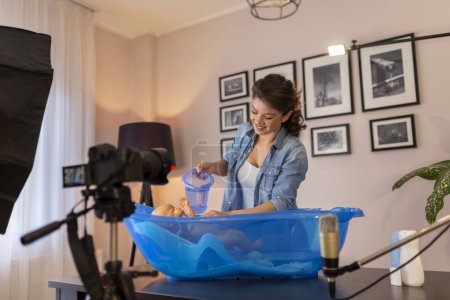 Weibliche Vlogerin dreht Video über das Baden von Neugeborenen im Rahmen von Online-Pränatalkursen; weibliche Influencerin filmt Tutorial über die Pflege von Neugeborenen