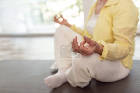 Téléchargez les photos : Détail de la femme âgée active pratiquant la méditation à la maison ; femme âgée faisant du yoga concept de mode de vie sain - en image libre de droit