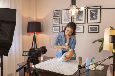 Photo for Female vlogger making a video about brushing newborn baby hair, parietal region and soft spot care as a part of online antenatal classes course - Royalty Free Image