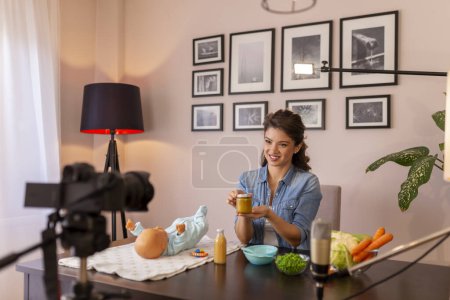 Photo for Influencer making tutorial about introducing soft food to baby nutrition and preparation of fresh fruit and vegetable porridges as part of online prenatal classes course - Royalty Free Image