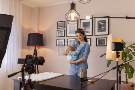 Téléchargez les photos : Influenceur faire une vidéo sur l'utilisation de porte-bébé mains libres dans le cadre de cours prénatals en ligne - en image libre de droit