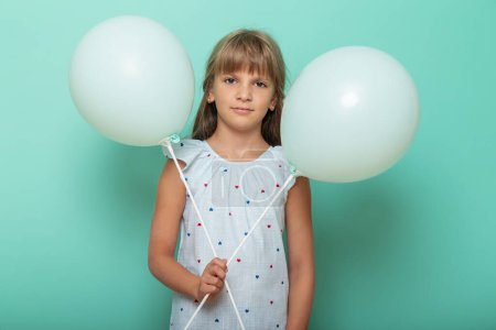 Foto de Retrato de una hermosa niña sosteniendo globos y sonriendo, aislado sobre fondo de color menta con espacio para copiar - Imagen libre de derechos
