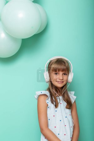 Foto de Retrato de una hermosa niña con auriculares y escuchando la música, aislada sobre fondo de color menta - Imagen libre de derechos