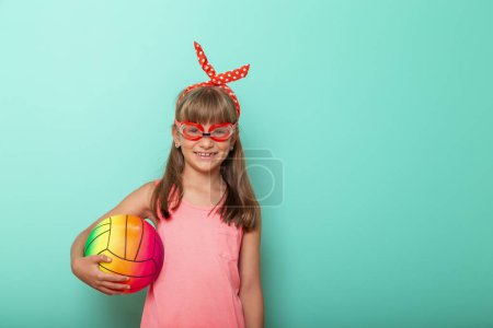 Photo for Portrait of beautiful little girl holding a beach volleyball ball and wearing swimming goggles, getting ready for summer holidays - Royalty Free Image