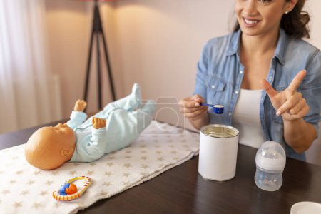 Photo for Influencer recording video about newborn baby bottle feeding and baby formula milk preparation as part of online prenatal classes - Royalty Free Image