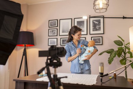 Photo for Influencer making tutorial about newborn baby care, baby handling and positioning as part of online prenatal classes - Royalty Free Image