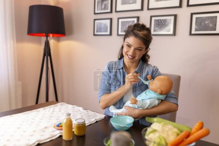 Photo for Female vlogger recording video about introducing a soft food into baby nutrition and feeding a baby as part of online birthing classes course - Royalty Free Image