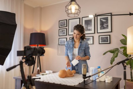 Photo for Female influencer recording educational newborn baby care videos about umbilical cord care and disinfection as part of online prenatal classes - Royalty Free Image