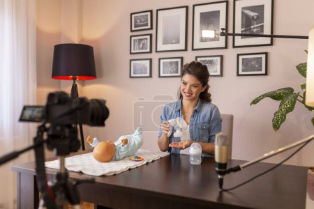 Foto de Tutorial de grabación de vlogger femenina sobre instrucciones de uso de extractor de leche como parte del curso de clases prenatales en línea - Imagen libre de derechos