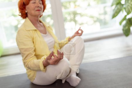 Téléchargez les photos : Femme âgée active pratiquant la méditation à la maison concept de mode de vie sain - en image libre de droit