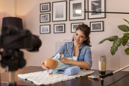 Photo for Female vlogger making video about newborn baby handling and positioning as part of online prenatal classes course - Royalty Free Image