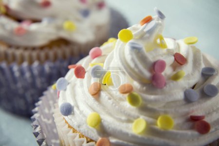 Foto de Primer plano de una crema con espolvoreos de colores en un cupcake - Imagen libre de derechos
