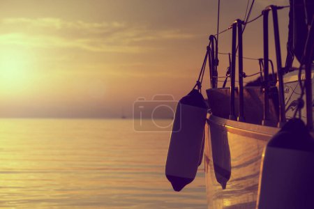 Photo for Detail of a boat anchored in the pear with buoys hanging from it on a sunset in Syvota bay - Royalty Free Image