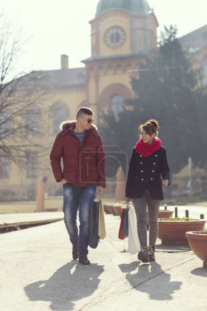 Téléchargez les photos : Beau jeune couple faisant du shopping et portant des sacs à provisions
. - en image libre de droit