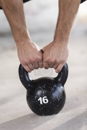 Photo for Close up of a young, muscular, athletic built man working out, lifting a kettlebell weight in an abandoned ruined building - Royalty Free Image