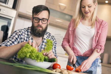 Téléchargez les photos : Couple amoureux couper des légumes et préparer le déjeuner ensemble. Concentrez-vous sur le gars - en image libre de droit