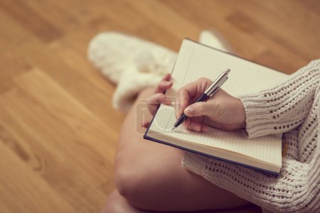 Photo for Detail of a young woman holding a planner and writing in her diary, enjoying winter days in a cozy home atmosphere - Royalty Free Image