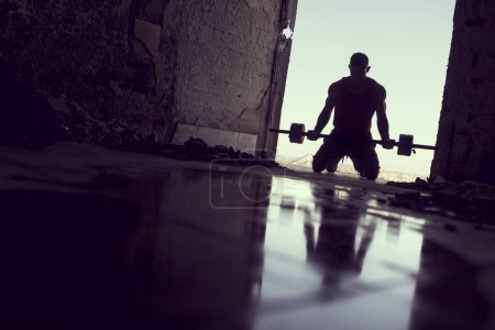 Photo for Muscular, athletic built, young athlete working out in a ruin building next to a puddle of water. Crossfit training with barbells and kettlebell deadlifting - Royalty Free Image