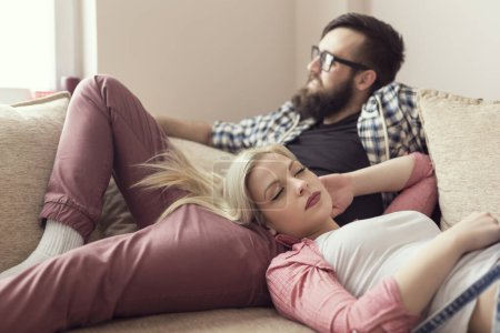 Téléchargez les photos : Jeune couple se reposant après une journée bien remplie au travail, couché sur un canapé. Concentre-toi sur la fille - en image libre de droit