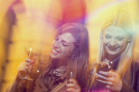 Foto de Dos amigas tomando cócteles y divirtiéndose en una noche de chicas - Imagen libre de derechos