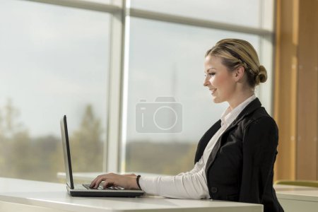 Foto de Joven mujer de negocios sentada en su escritorio en una oficina, trabajando en una computadora portátil y planeando un nuevo proyecto - Imagen libre de derechos