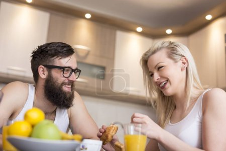 Photo for Couple in love sitting at a kitchen table, having a breakfast together. Focus on a man - Royalty Free Image
