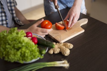 Photo for Detail of a couple in love cutting vegetables and preparing lunch together - Royalty Free Image