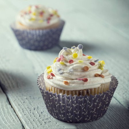 Photo for Close up of a nicely decorated cupcakes isolated on light blue wooden boards - Royalty Free Image