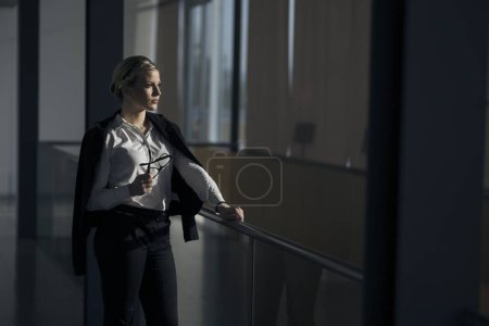 Téléchargez les photos : Femme d'affaires forte, confiante, debout dans un couloir d'immeuble de bureaux - en image libre de droit