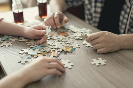 Photo for Couple in love sitting on the floor next to a table, solving a jigsaw puzzle problem and enjoying their leisure time activities. - Royalty Free Image