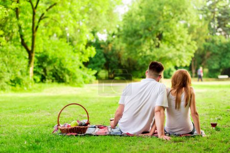 Photo for Couple sitting on a picnic blanket, both pensive, enjoying the peace and nature - Royalty Free Image