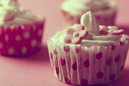 Téléchargez les photos : Gros plan d'un cupcakes joliment décoré isolé sur fond rose - en image libre de droit