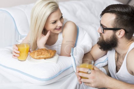 Photo for Couple in love wearing pajamas and having a breakfast in bed. - Royalty Free Image