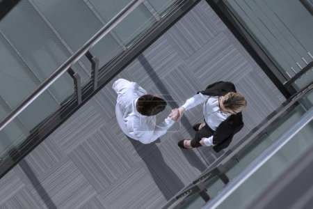 Téléchargez les photos : Vue du dessus d'un homme d'affaires confiant et d'une femme serrant la main dans un hall d'entrée d'immeuble de bureaux - en image libre de droit