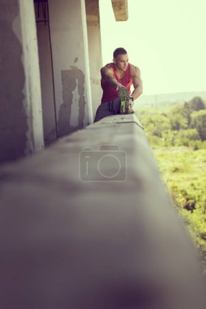 Foto de Musculoso, atlético, joven esparciéndose en un edificio en ruinas antes del entrenamiento - Imagen libre de derechos