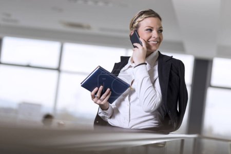 Photo for Modern business woman having a phone conversation with a colleague - Royalty Free Image