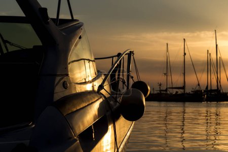 Téléchargez les photos : Détail d'un bateau ancré dans la poire avec des bouées suspendues à elle sur un coucher de soleil dans la baie de Syvota - en image libre de droit