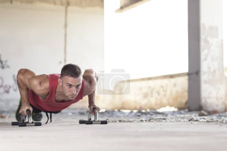 Photo for Muscular, athletic built, young man doing pushups in an abandoned ruin building - Royalty Free Image