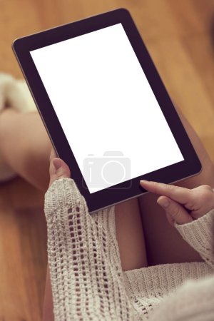 Téléchargez les photos : Détail d'une jeune belle femme assise sur le sol en bois, portant un pull et des bottes à la maison et utilisant un ordinateur tablette. Mettre l'accent sur le doigt pointeur - en image libre de droit