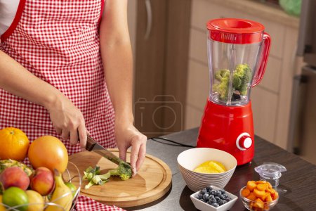Téléchargez les photos : Détail des mains féminines coupant le brocoli afin de faire un bouillon de légumes dans un mélangeur - en image libre de droit