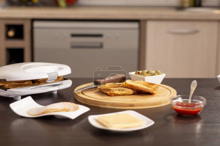 Téléchargez les photos : Sandwichs chauds prêts pour le petit déjeuner servis sur une planche à découper en bois sur une table de cuisine - en image libre de droit
