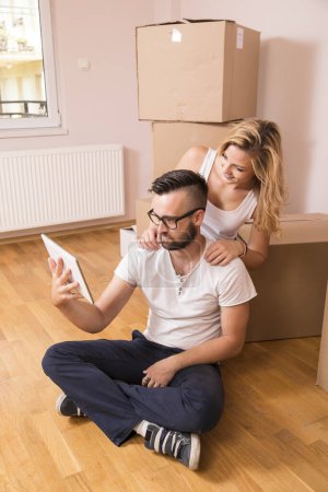 Téléchargez les photos : Jeune couple amoureux déménageant dans un nouvel appartement, assis sur le sol, prévoyant de redécorer leur nouvelle maison - en image libre de droit