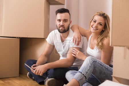 Photo for Young couple in love moving in a new apartment, sitting on the floor, planning to redecorate their new home - Royalty Free Image