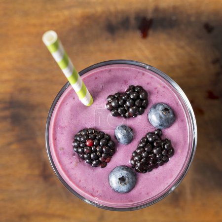 Photo for Top view of a blueberry smoothie in a glass placed on a rustic table - Royalty Free Image
