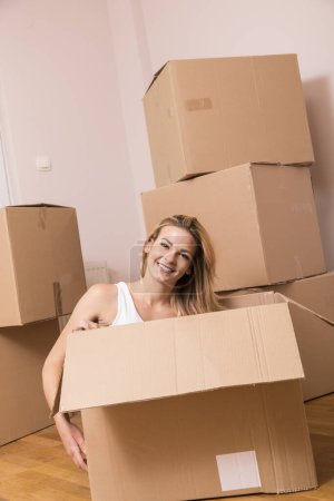 Téléchargez les photos : Femme assise à l'intérieur d'une boîte en carton pendant l'emballage - en image libre de droit