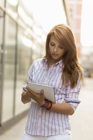 Téléchargez les photos : Jeune femme d'affaires travaillant sur sa tablette à l'extérieur du bureau - en image libre de droit