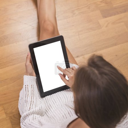 Téléchargez les photos : Détail d'une jeune belle femme assise sur le sol en bois, portant un pull et utilisant une tablette - en image libre de droit